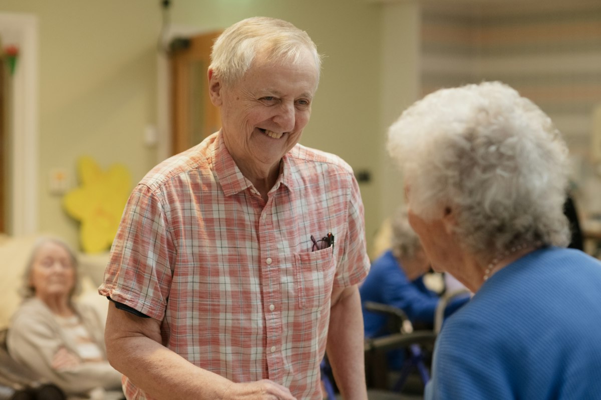 Two smiling older neighbors talking together in a community room